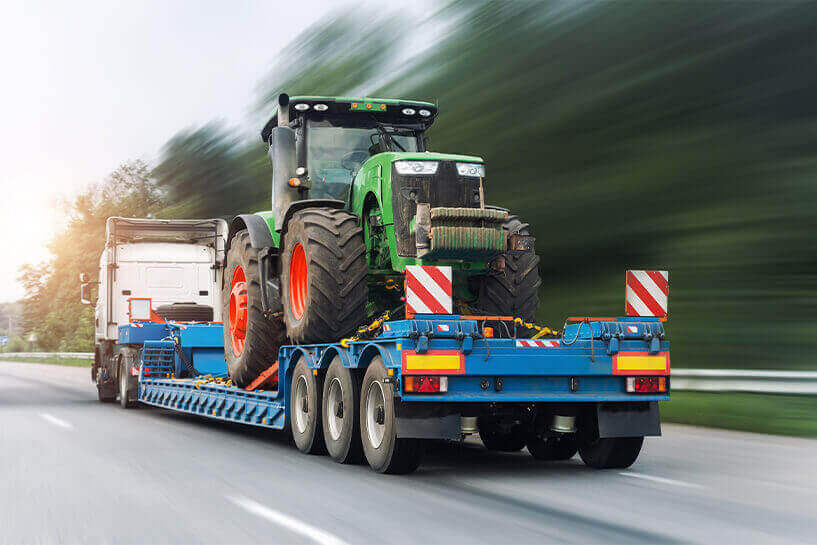 Semi Hauling a Tractor, to Represent Consignment